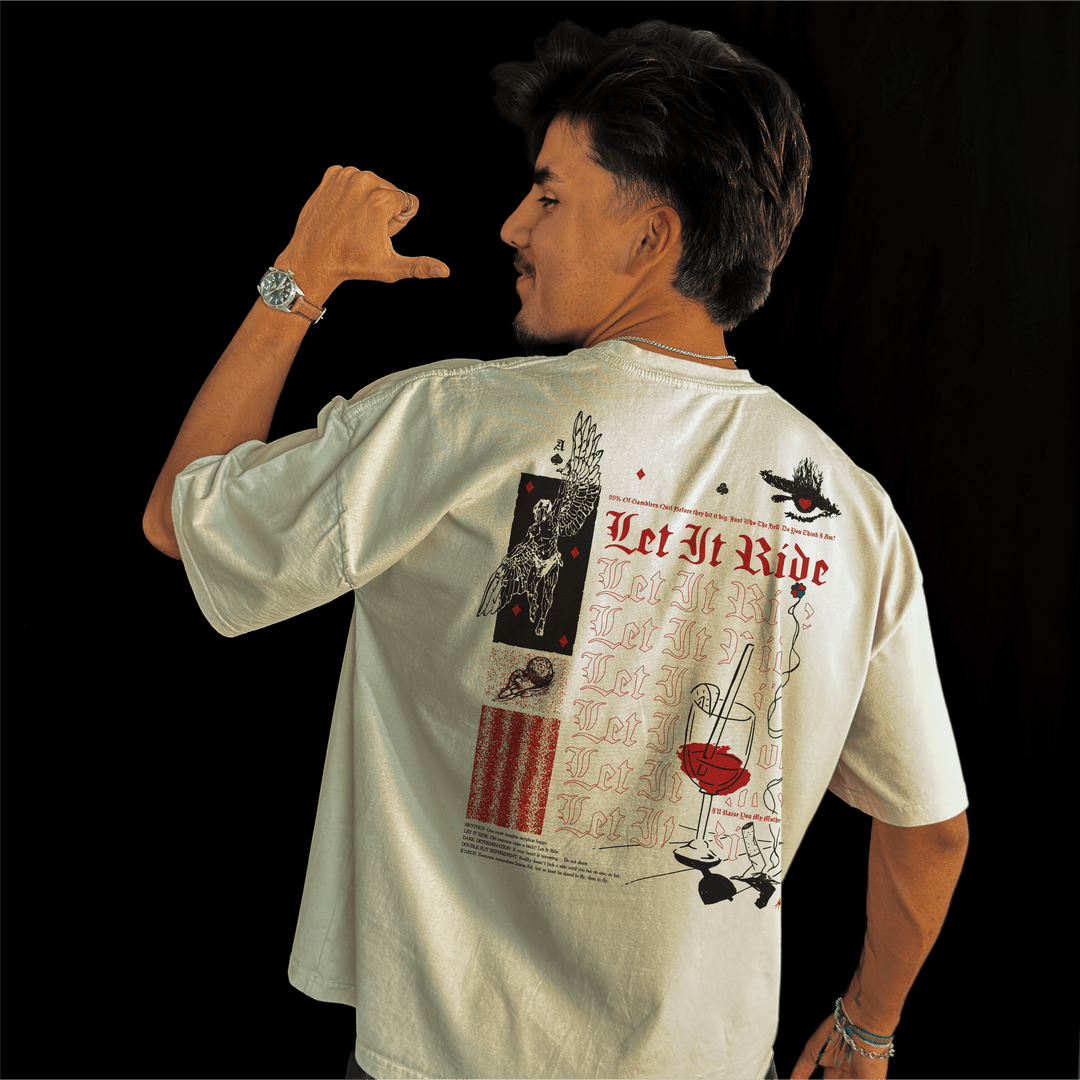 Man wearing the Let It Ride oversized tee in bone, pointing a thumb at the back print