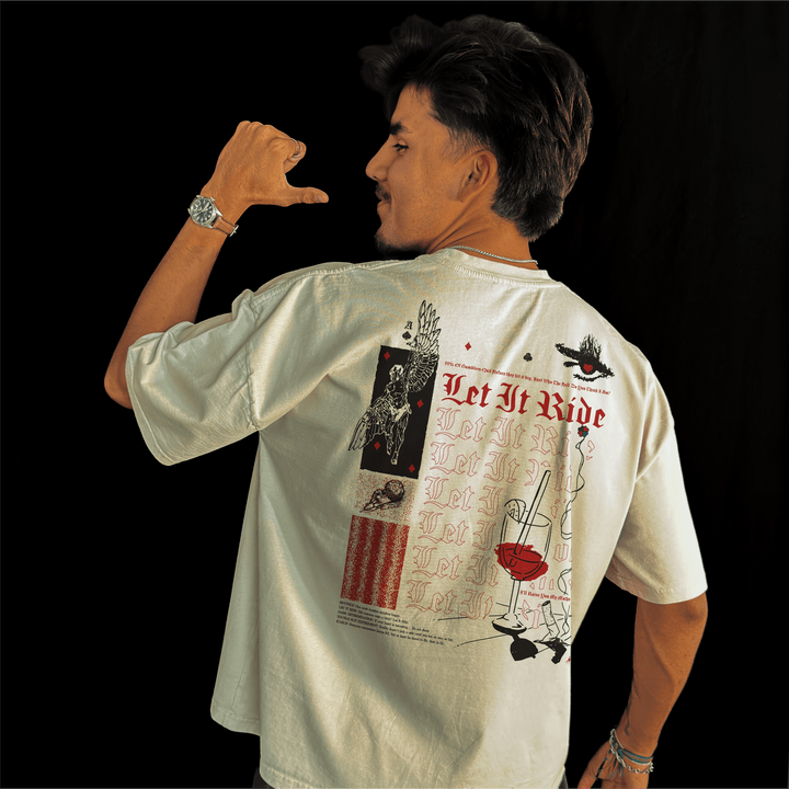 Man wearing the Let It Ride oversized tee in bone, pointing a thumb at the back print