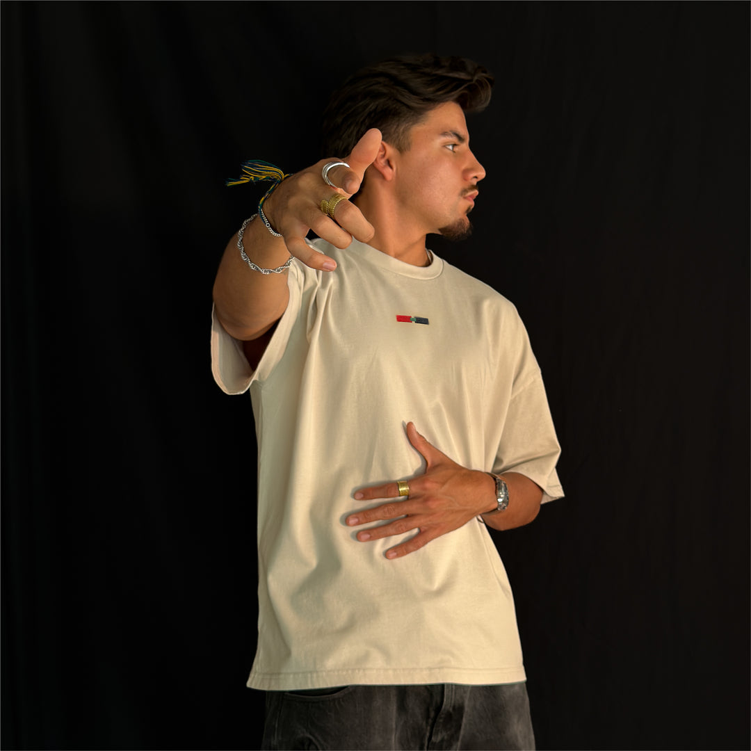 Man wearing the Let It Ride oversized tee in bone, front view with his head turned to the side, showing the chest stripe
